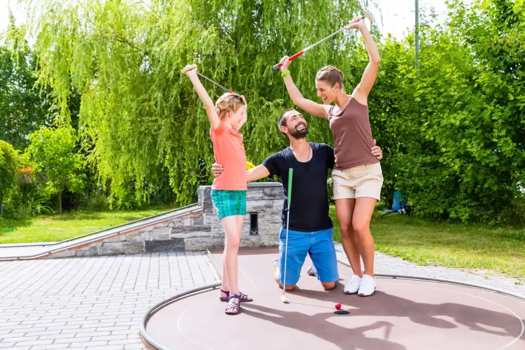 A family of three maximizes time together on vacation by playing miniature golf.