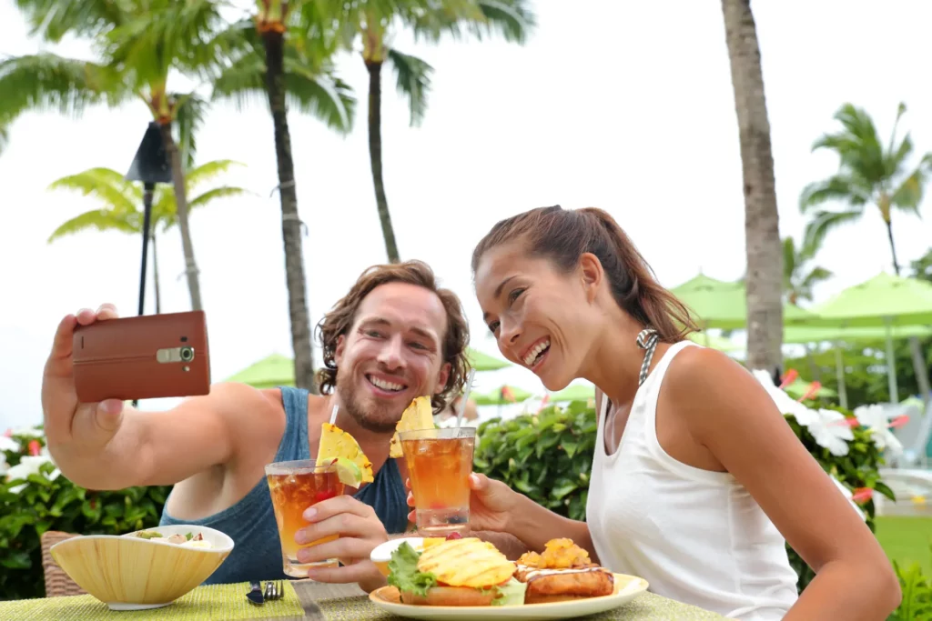 A couple maximize their time together on vacation by eating a meal together outside at a beach-side restaurant.