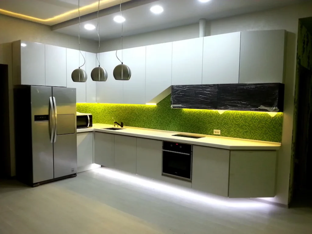 LED strips add a soft, white stream of light beneath a row of kitchen cabinets and countertops.
